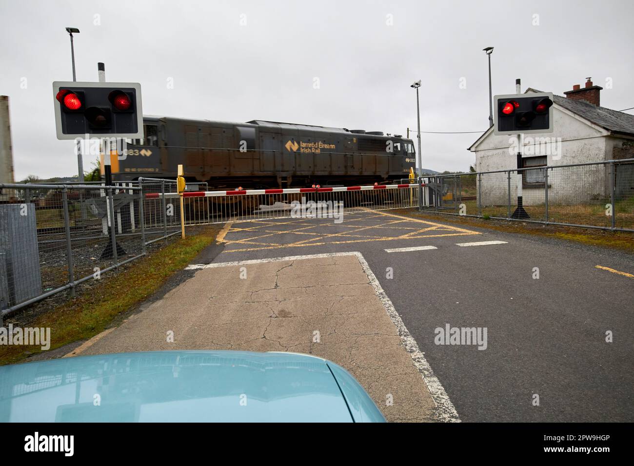 treno irlandese merci ferroviario che passa come auto in attesa di attraversamento del livello ferroviario con barriera al di sotto della contea mayo repubblica d'irlanda Foto Stock