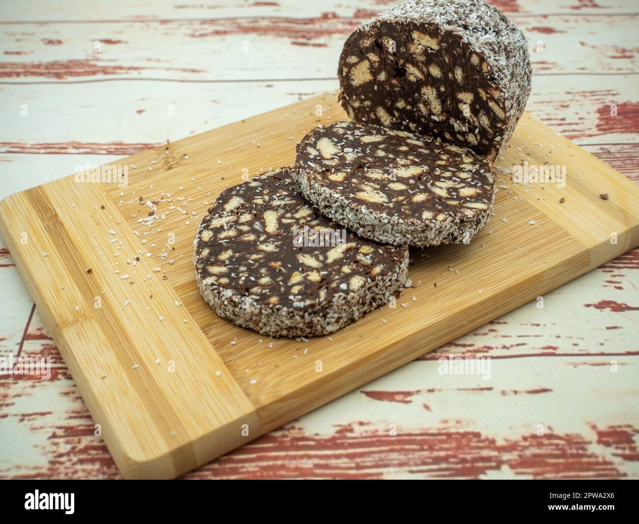 affetta il salame al cioccolato con biscotti su un tagliere Foto Stock