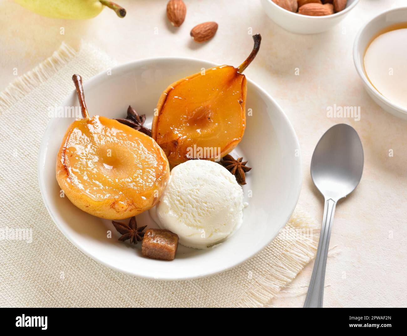 Palla di gelato con pere in camicia in ciotola su sfondo di pietra chiara. Foto Stock