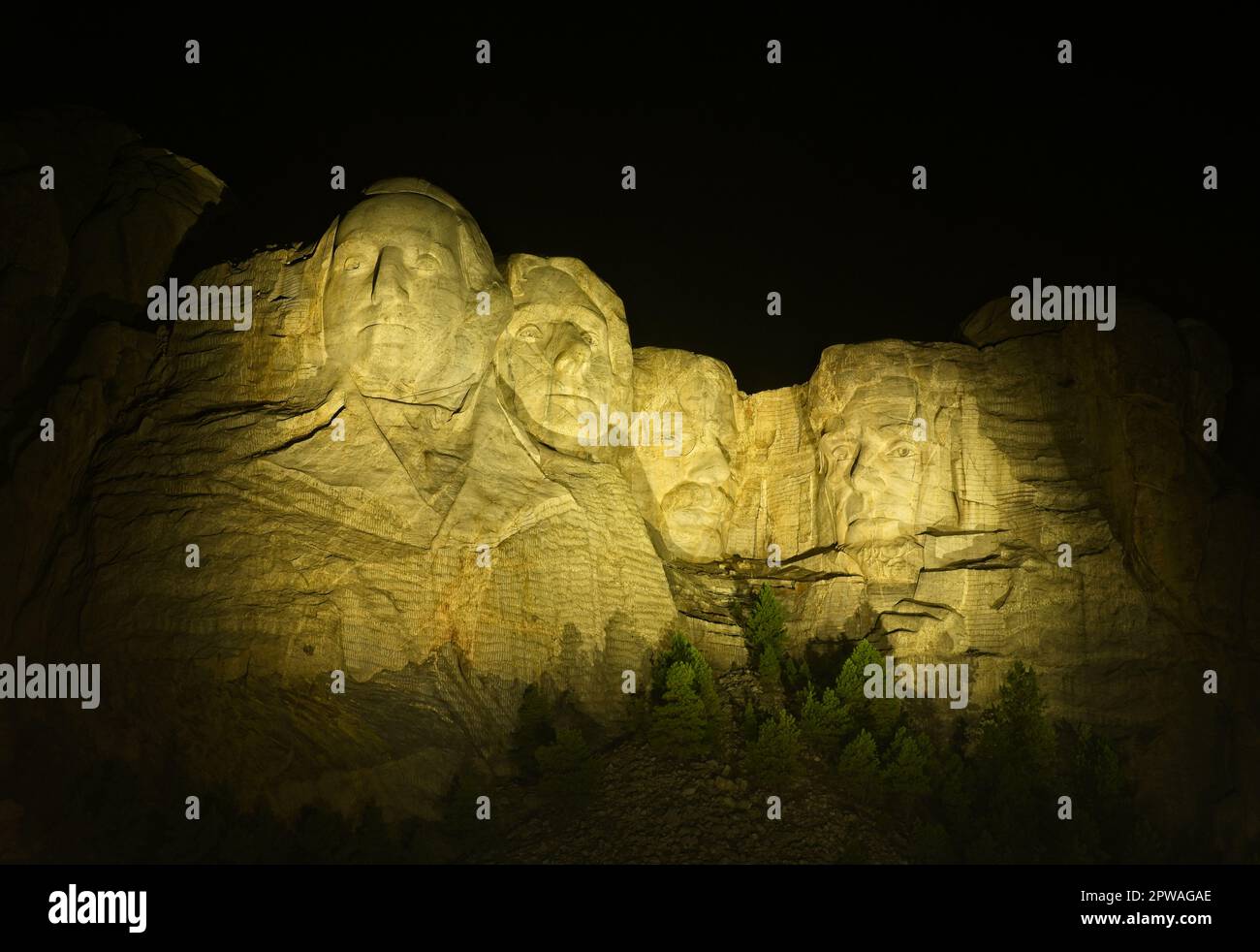 I quattro presidenti del Monte Rushmore sono illuminati di notte da un cielo nero Foto Stock
