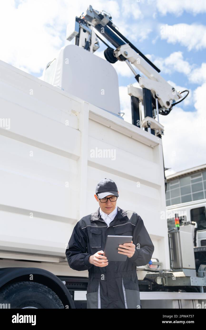 Manager con un tablet digitale accanto al veicolo per la raccolta rifiuti. Foto di alta qualità Foto Stock