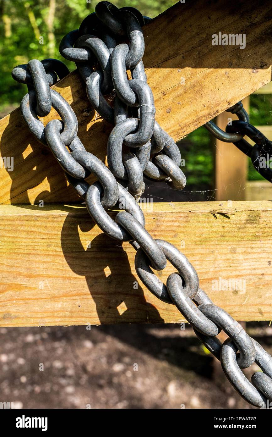 Grande catena metallica avvolta intorno ad un cancello di legno. Concetto di forza, sicurezza, legato, confezionato, sicuro, bloccato, concatenato Foto Stock