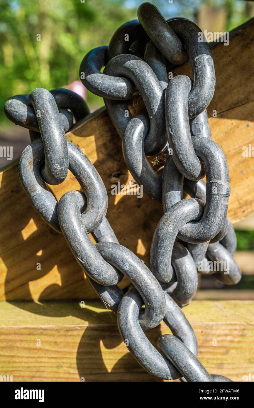 Grande catena metallica avvolta intorno ad un cancello di legno. Concetto di forza, sicurezza, legato, confezionato, sicuro, bloccato, concatenato Foto Stock