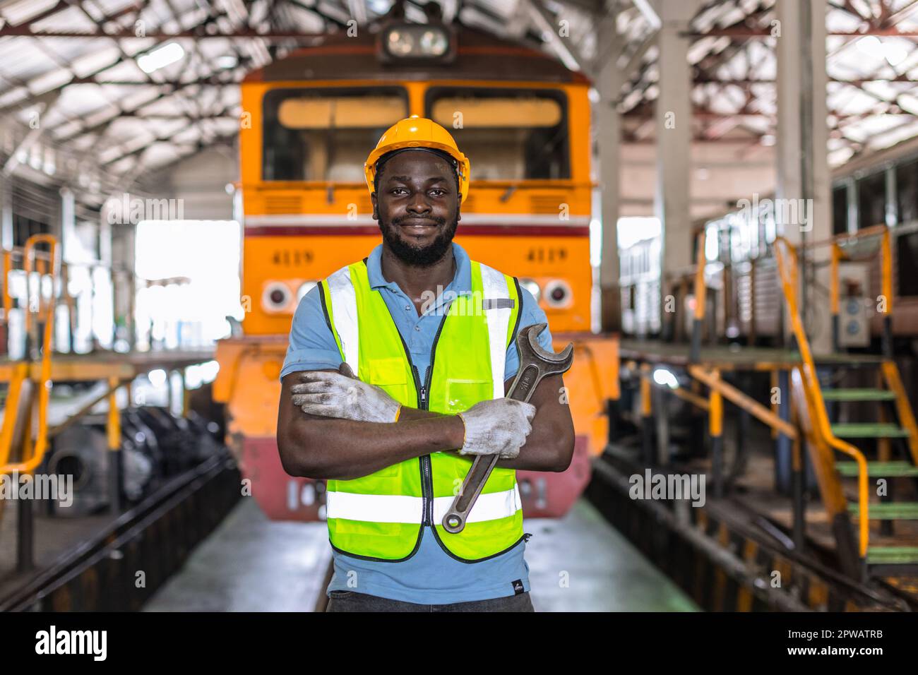 Ritratto Africano nero lavoro maschile in locomotiva riparazione Negozi in piedi felice sorridendo con la chiave Foto Stock