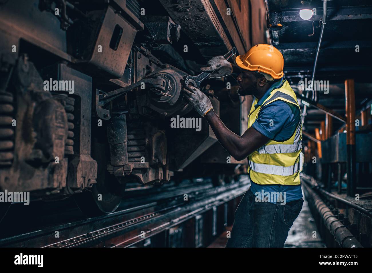 un addetto alla manutenzione sostituisce la parte rotta del vecchio treno presso le officine di riparazione di locomotive diesel Foto Stock