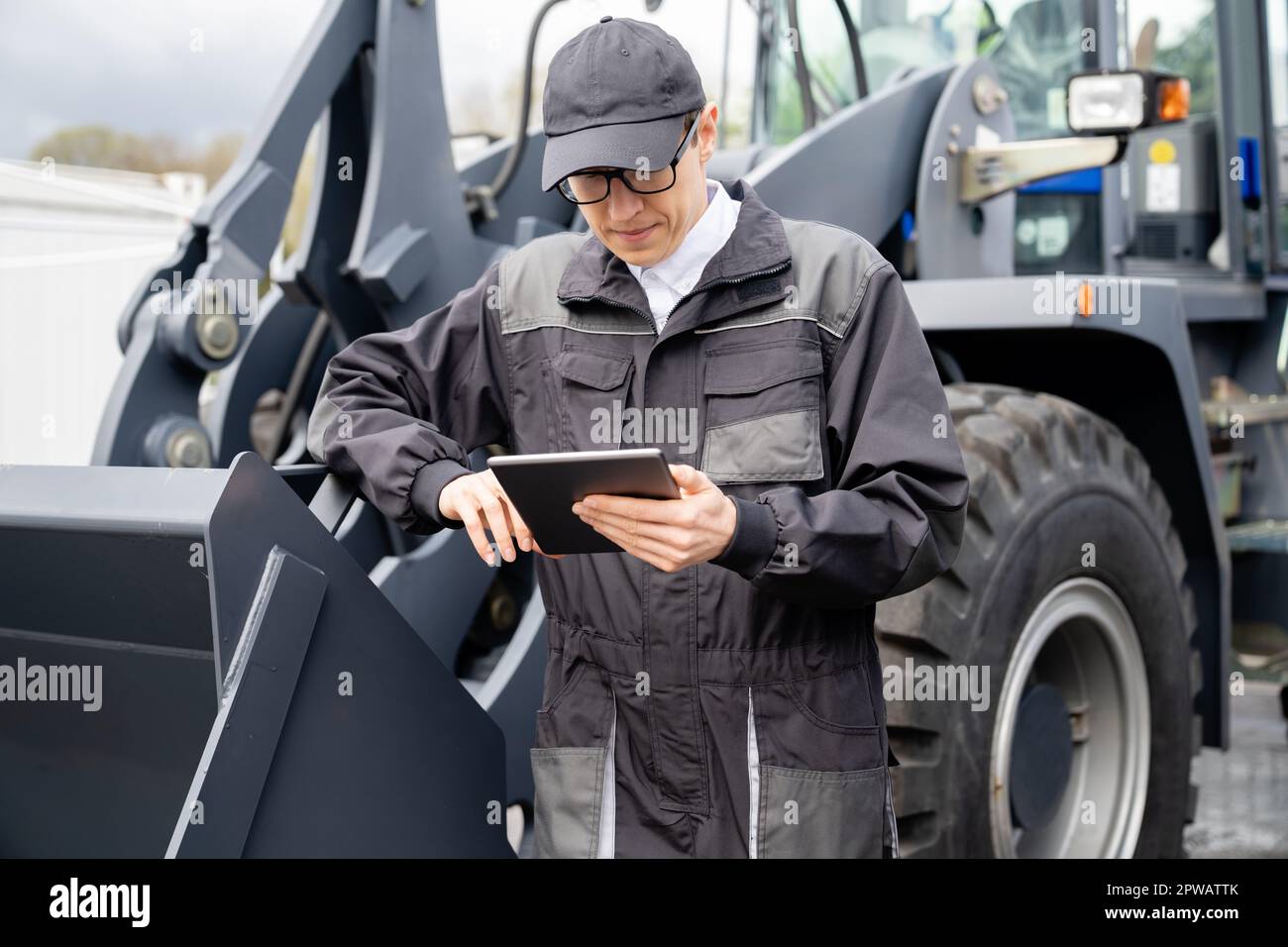 Addetto alla manutenzione con tablet digitale sullo sfondo del trattore. Foto di alta qualità Foto Stock