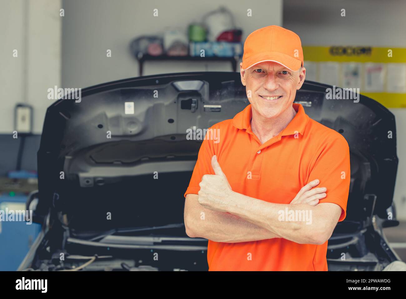 Meccanico di automobile di sguardo professionale anziano in piedi in garage. Ritratto felice sorridente caucasico adulto maschio in Auto Service Thumbs up. Foto Stock