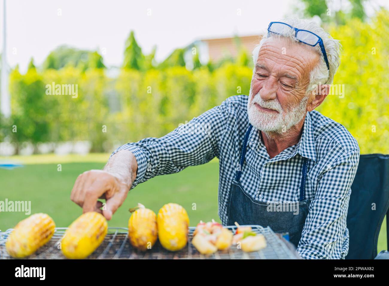 Sano uomo anziano senior maschio relax stile di vita cucina cibo grill mais cortile all'aperto Foto Stock