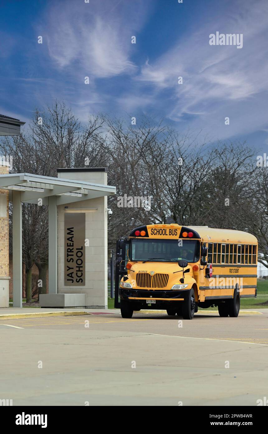 Carol Stream, Illinois, USA. Un scuolabus che attende i passeggeri da un ingresso a una scuola media pubblica suburbana di Chicago. Foto Stock
