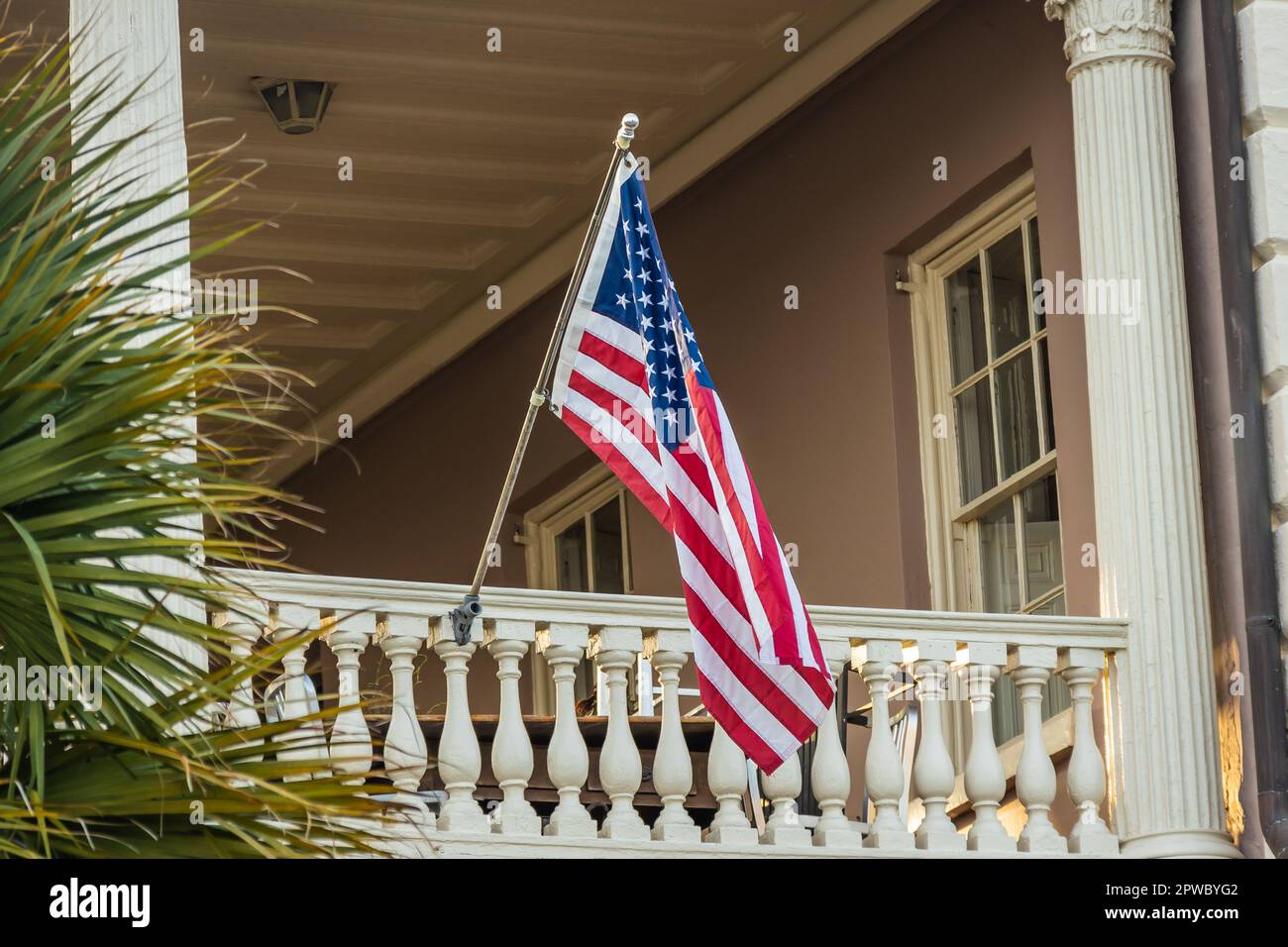 Una bandiera americana appesa al di fuori di una casa di epoca coloniale alla luce del mattino. Foto Stock