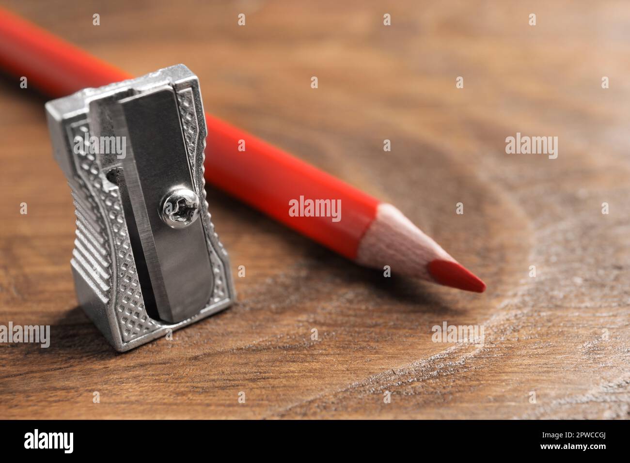 Affilatore di metallo e matita rossa su tavolo di legno, primo piano.  Spazio per il testo Foto stock - Alamy