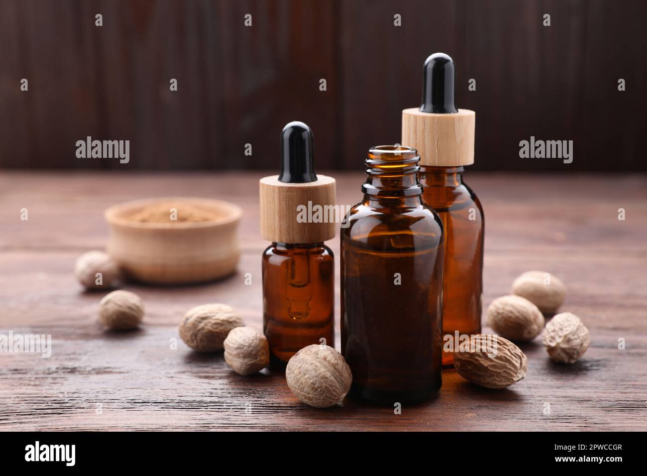 Bottiglie di olio di noce moscata e noci su tavola di legno Foto Stock