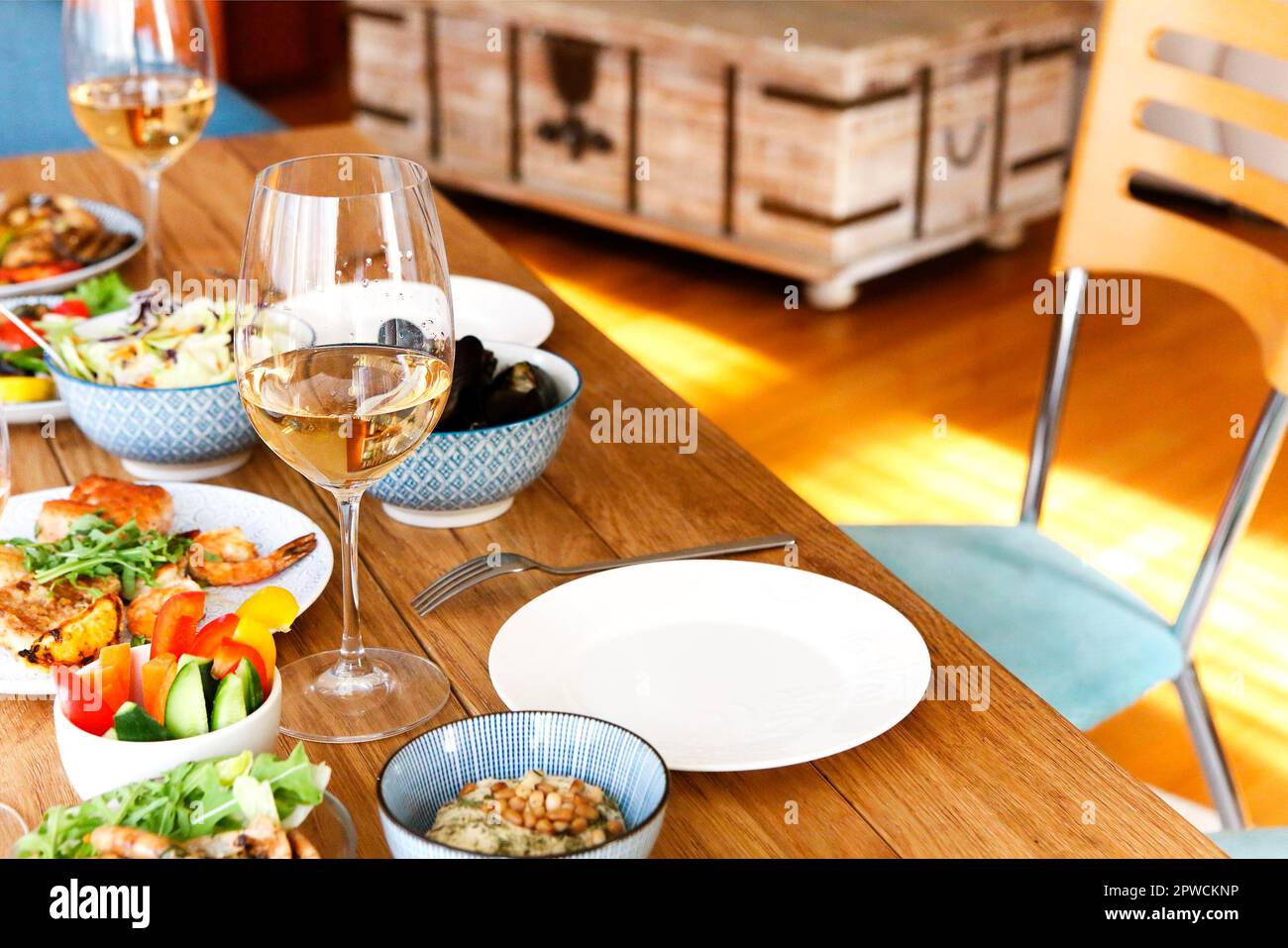 Un angolo alto di tavolo in legno servito con vari piatti fatti in casa e bicchieri con vino in un accogliente soggiorno a casa Foto Stock