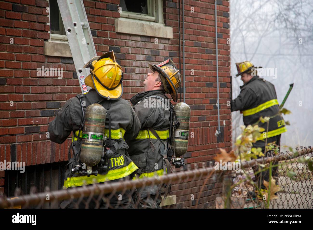 Detroit, Michigan, indossando serbatoi d'aria, i vigili del fuoco hanno messo in campo una scala mentre combattono un incendio che ha danneggiato una casa nel quartiere Morningside di Detroit Foto Stock