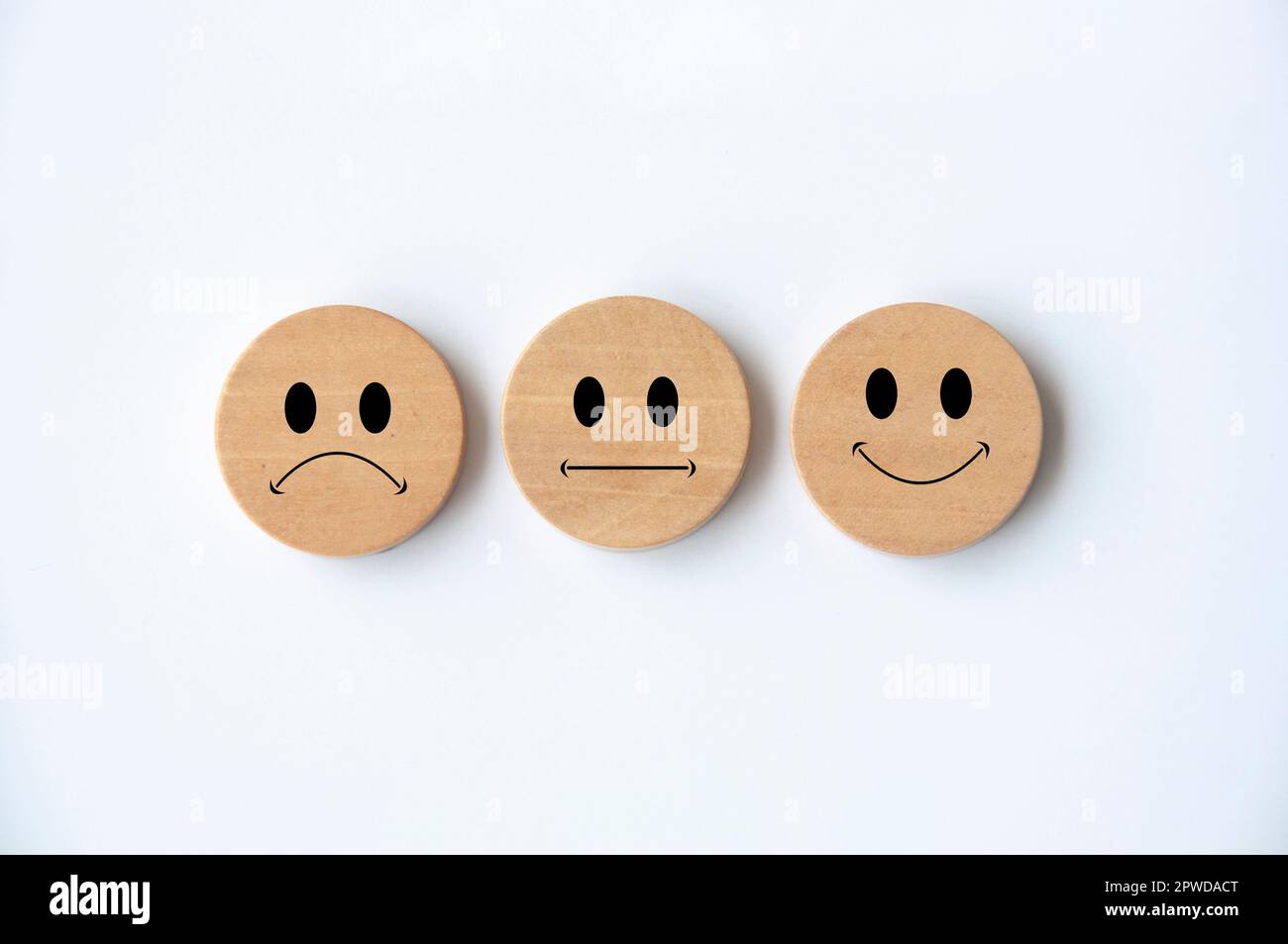 Faccine emoticon felici, tristi e neutrali su cerchio di legno con copertura di fondo bianca. Feedback dei clienti, soddisfazione, valutazione e concetto. Foto Stock