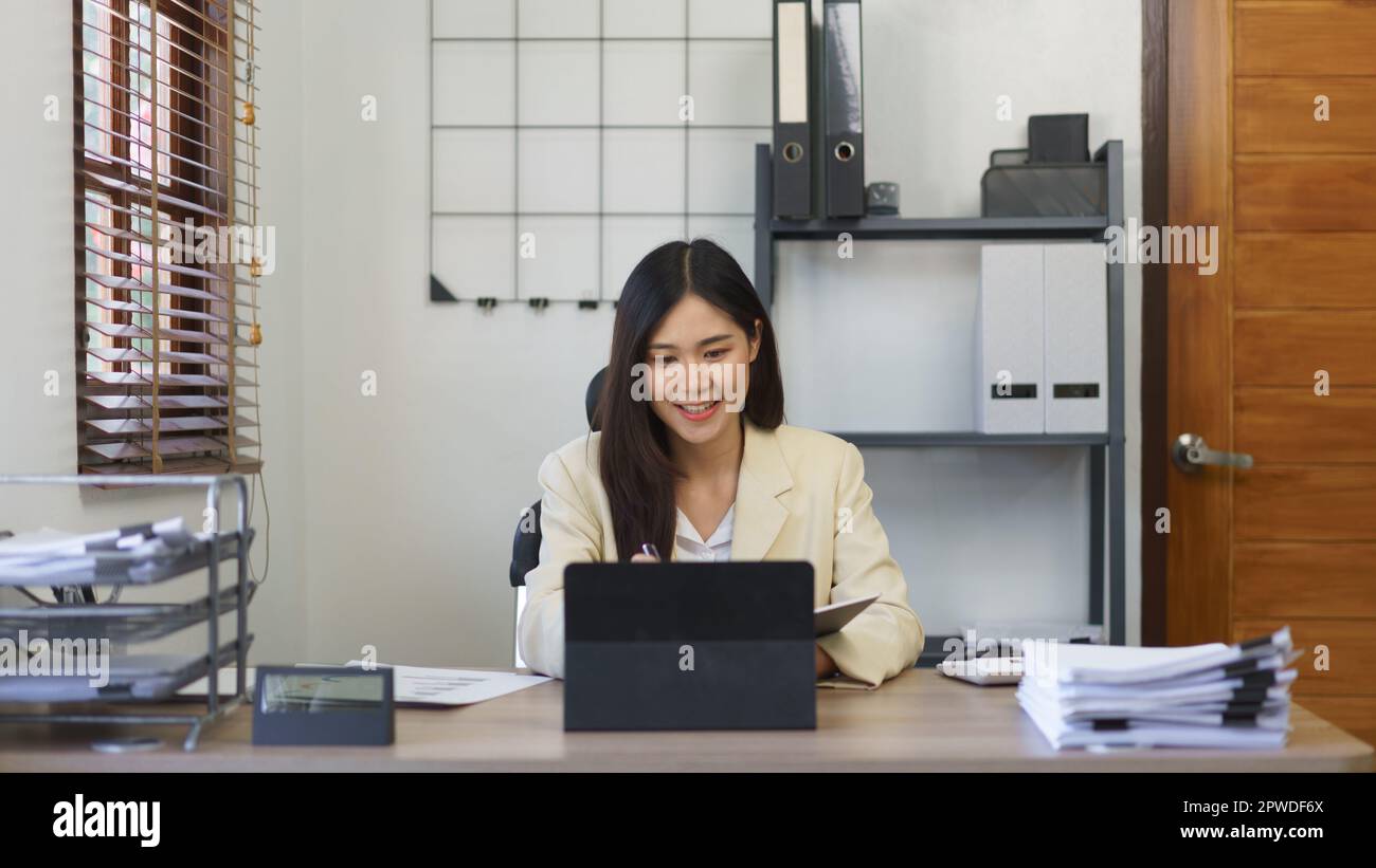 Secretary Concept, Female Secretary che prende appunti in notebook e reading report business su tablet. Foto Stock