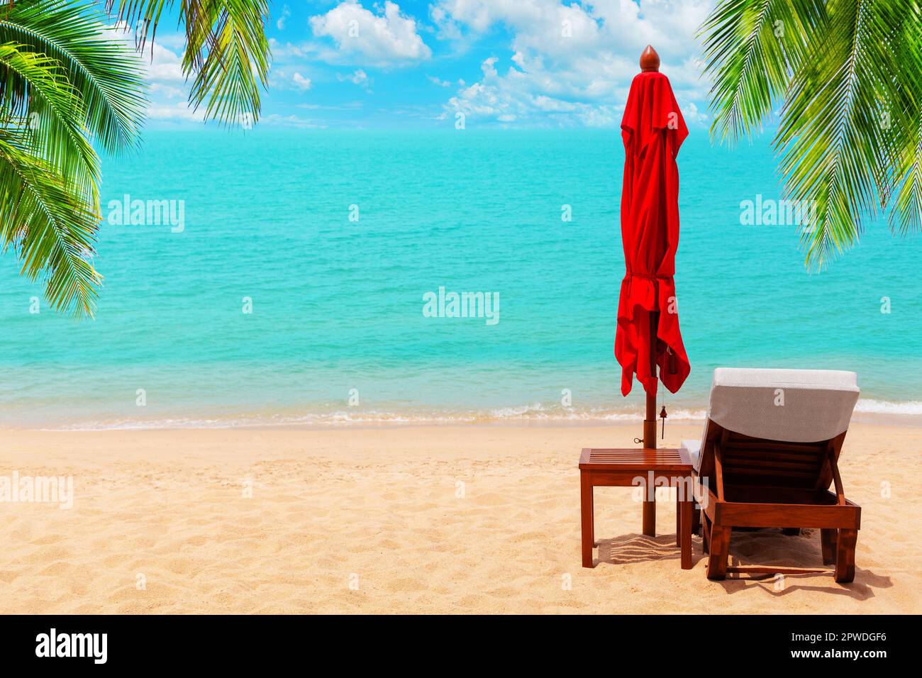 Ombrello rosso, sedia a sdraio vuota, ombrellone solare, lettino, chaise longue in legno, lettino solare, foglie di palma verde, paradiso tropicale isola mare spiaggia Foto Stock