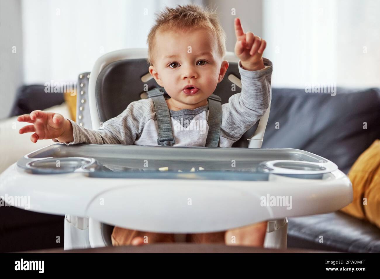 HES abbastanza il mangiatore picky. un ragazzino carino seduto sulla sedia da allattamento. Foto Stock