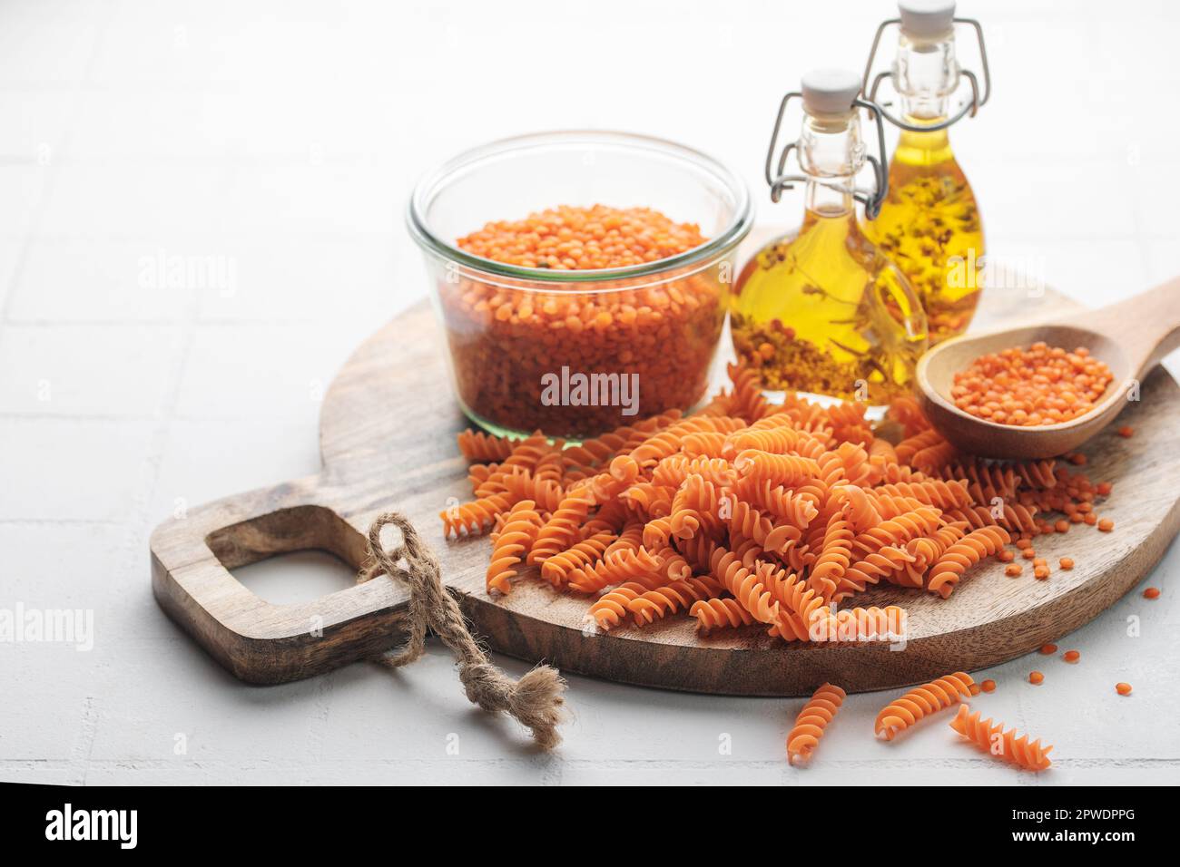 Lenticchie rosse fusilli su fondo grigio in cemento. Ciotola con pasta cruda e lenticchie rosse. Pasta senza glutine. Foto Stock