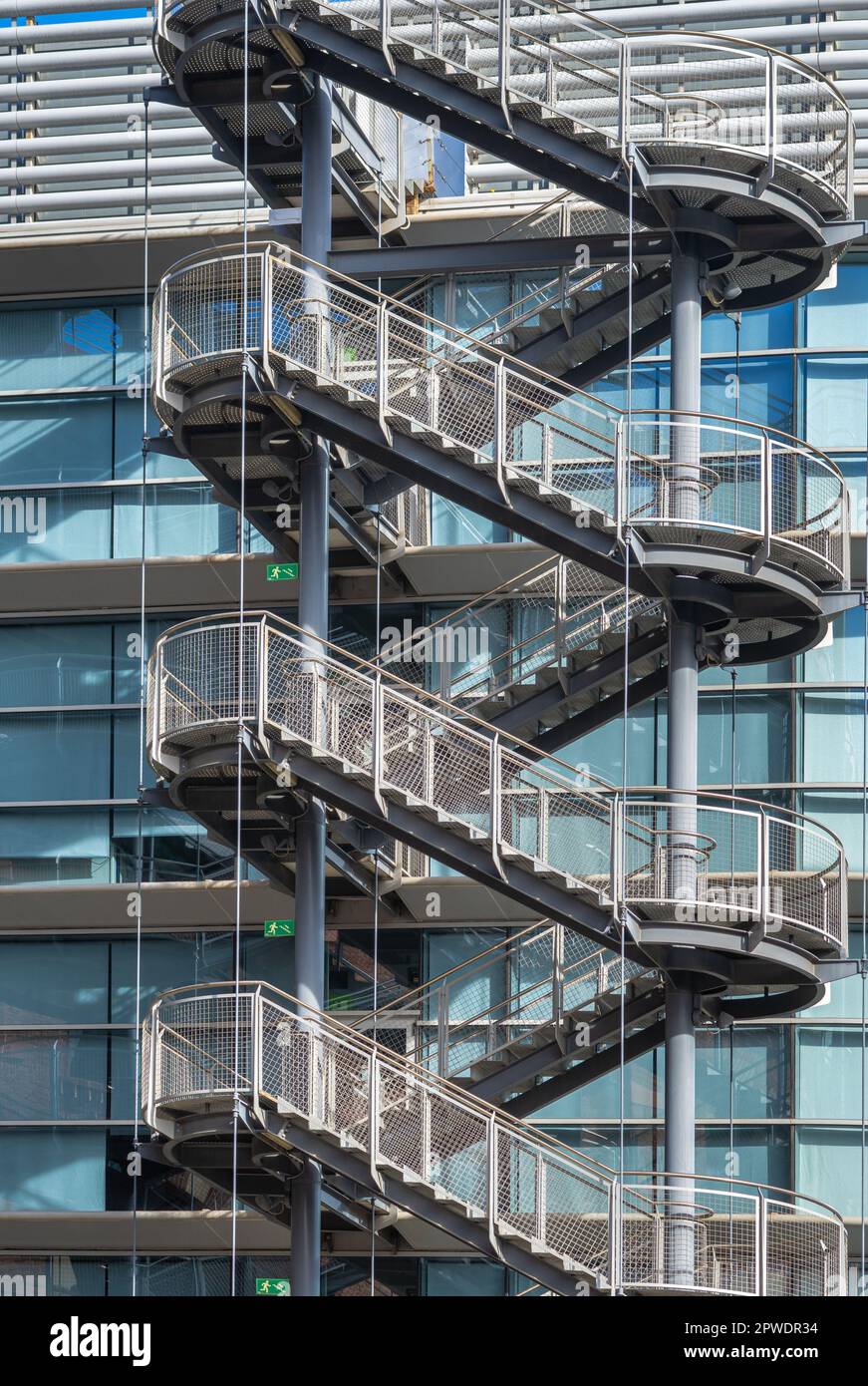 Scala di ferro a zig zag per la fuga dal fuoco al di fuori della moderna recinzione di edifici industriali in metallo all'aperto. Foto Stock