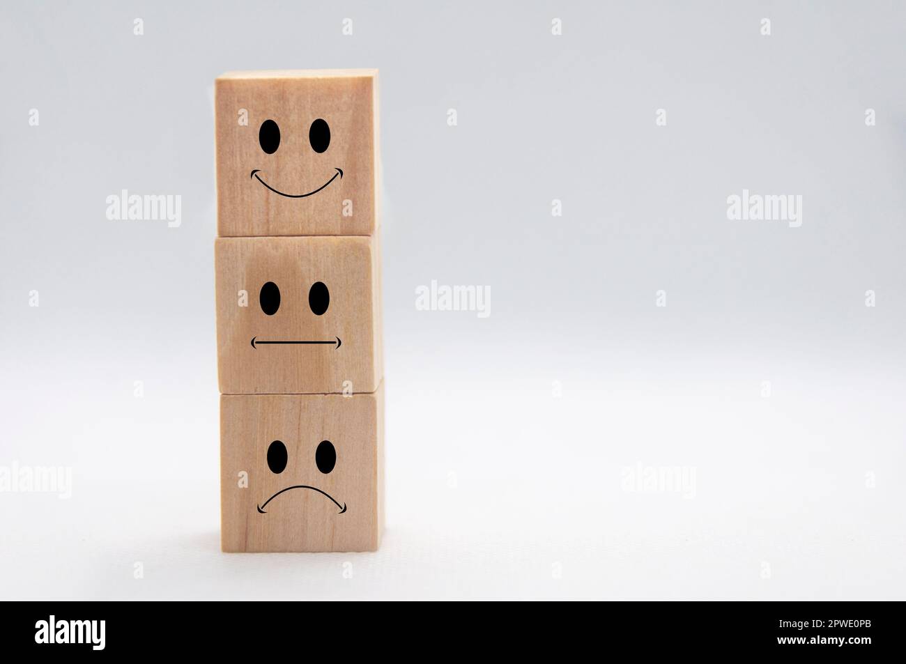 Facce emoticon felici, tristi e neutrali su cubi di legno impilabili con copertura di fondo bianca. Soddisfazione del cliente e concetto di valutazione Foto Stock
