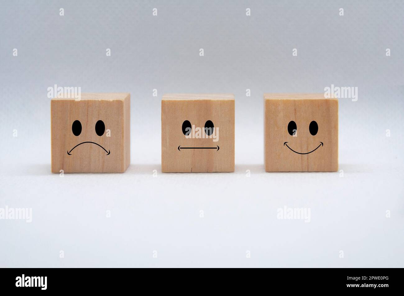 Faccine emoticon tristi, neutrali e felici su cubetti di legno con copertura di fondo bianca. Feedback dei clienti, soddisfazione e valutazione. Foto Stock
