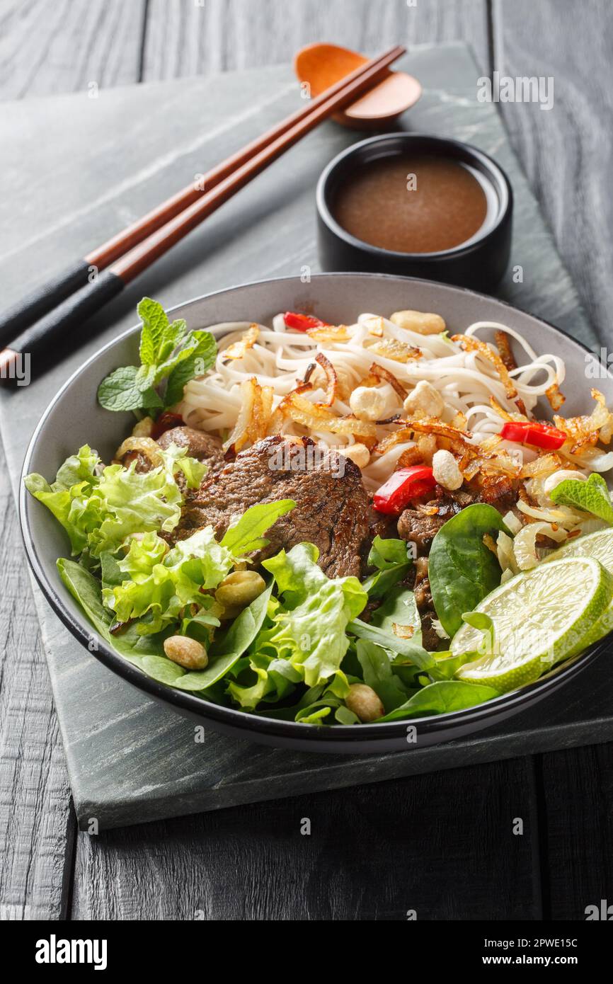 Insalata di noodle di manzo vietnamita Pho Tron primo piano sul piatto sul tavolo di legno. Verticale Foto Stock