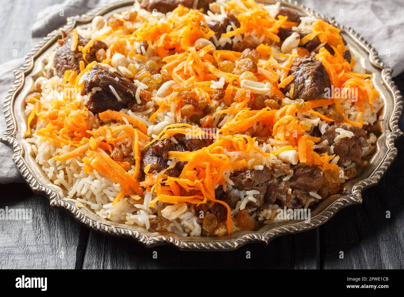 Piatto nazionale afghano Kabuli Pulao riso pilaf con agnello e uva passa, carota, noci, spezie primo piano sul piatto sul tavolo di legno. Orizzontale Foto Stock