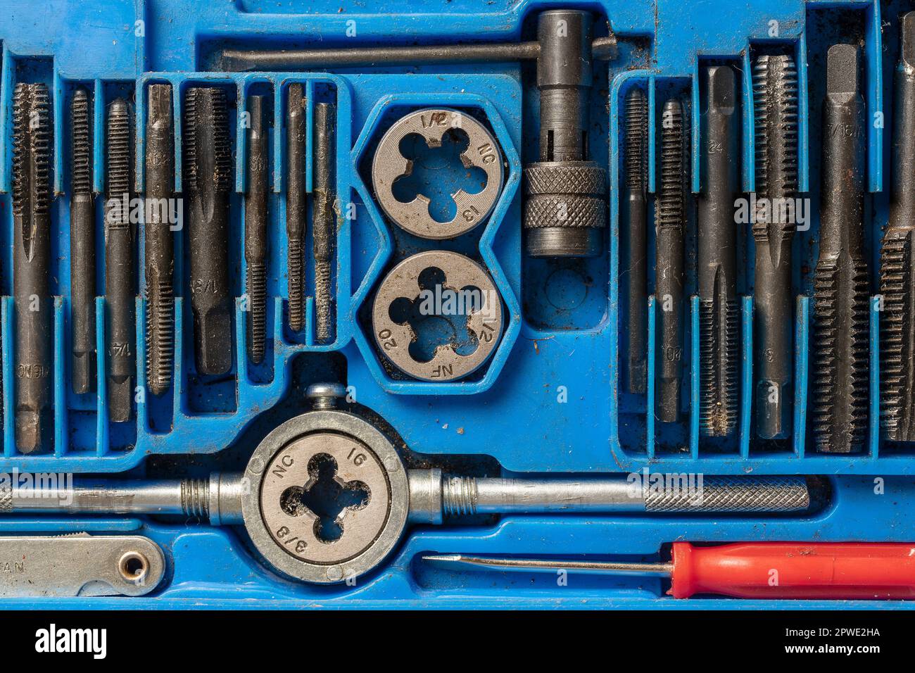 Molti stampi metallici e supporti per loro di diverse dimensioni per la filettatura in scatola blu. Utensile manuale per filettatura, primo piano, vista dall'alto. Utensile per il taglio e Foto Stock