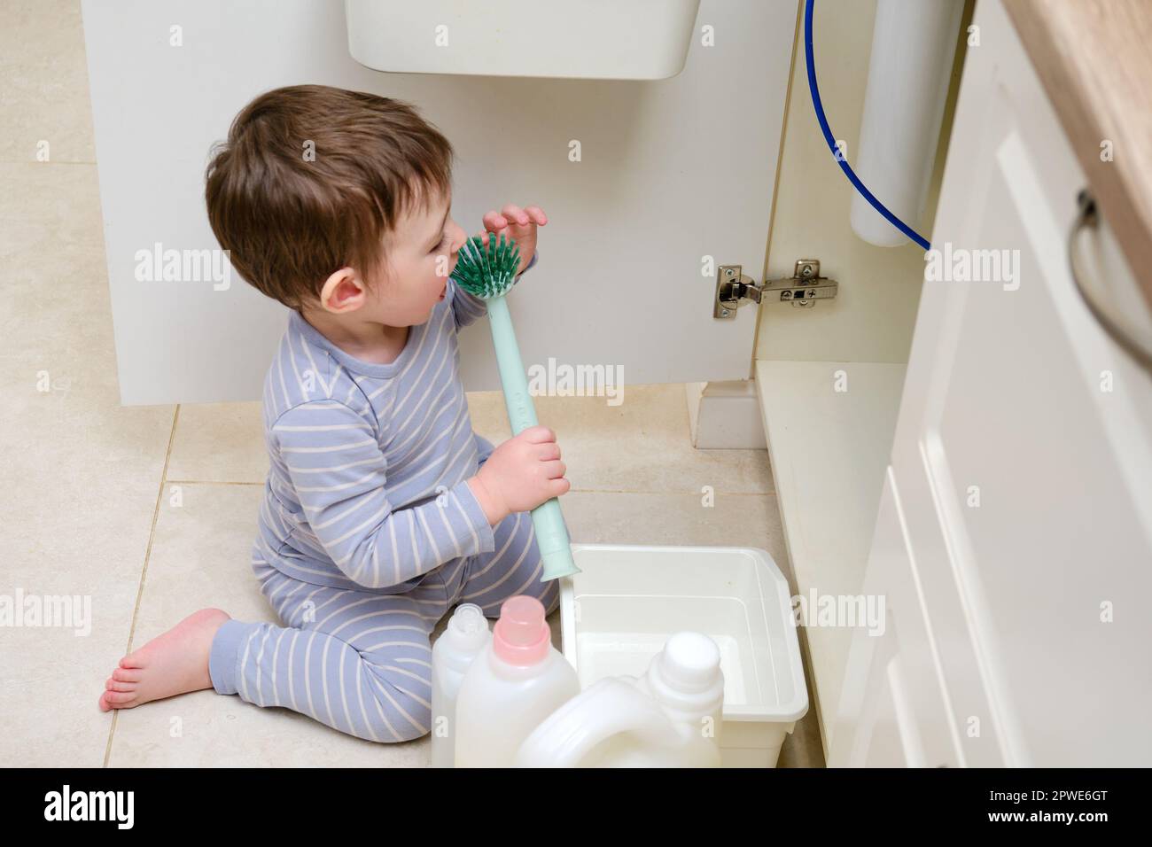 Un bambino gioca con prodotti chimici per la pulizia sotto il lavandino in  cucina. Il bambino può contenere biberon con detergente. Bambino di circa  due anni (uno yea Foto stock - Alamy