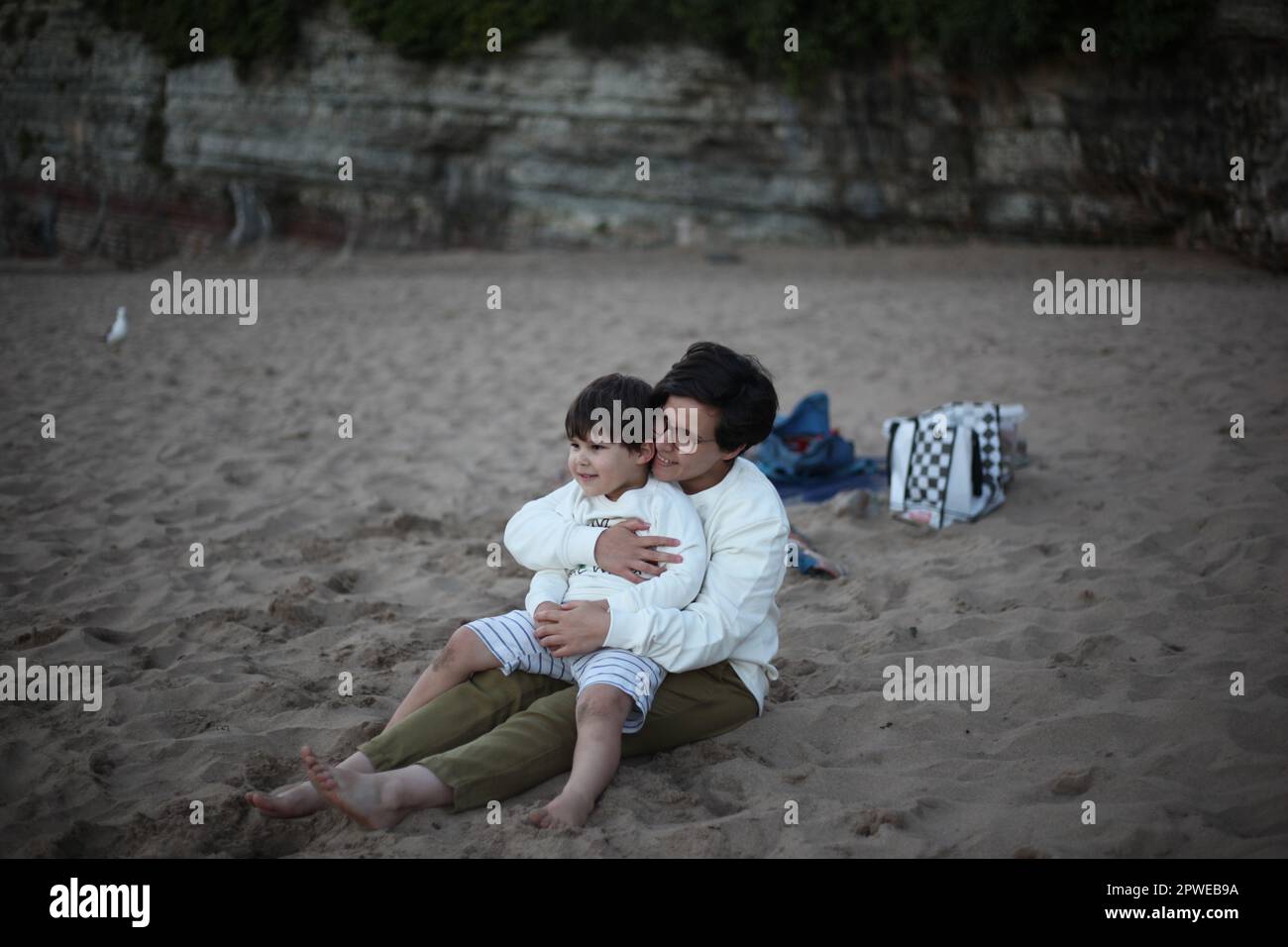 Madre e Figlio seduti sulla spiaggia Foto Stock