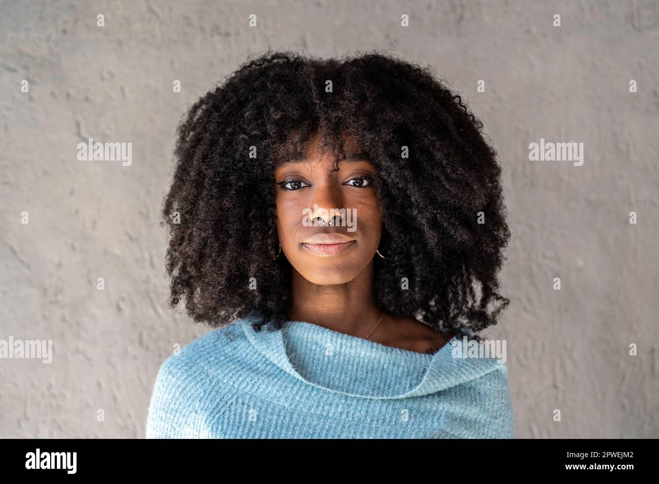 Ritratto di felice ragazza afroamericana - capelli ricci donna cubana con  piercing al naso che posa di fronte alla macchina fotografica su uno sfondo  grigio - giovane Foto stock - Alamy