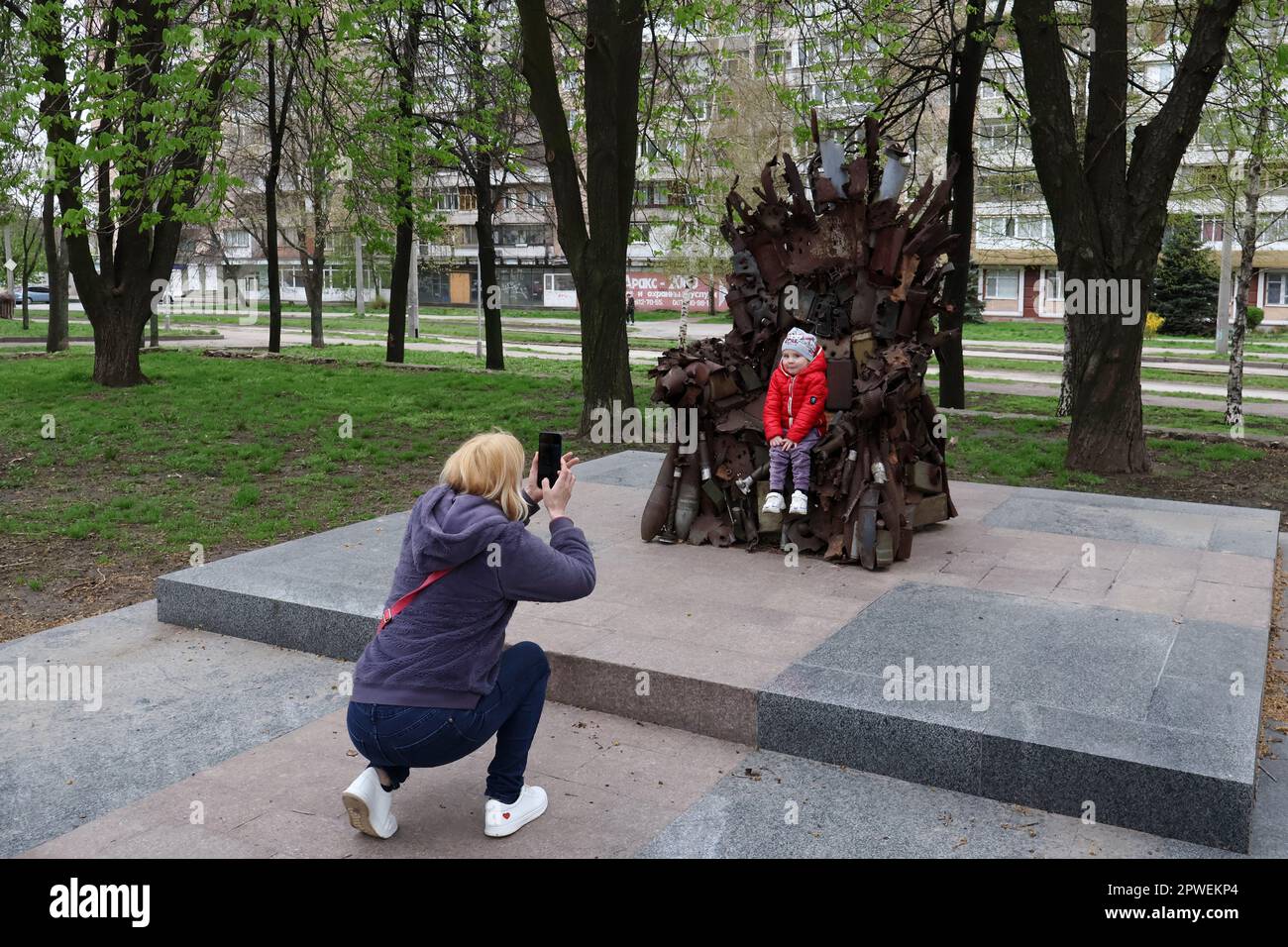 Zaporizhzhzhia, Ucraina. 15th Apr, 2023. La moglie del soldato dell'esercito ucraino è vista scattando una foto della loro figlia al trono di ferro dell'est nel centro di Zaporizhzhia. Il Trono di ferro dell'Est a Zaporizhzhzhia, Ucraina, fatto di veri e propri macchinari militari, relitti e conchiglie. Fu fatto nelle posizioni delle forze armate dell'Ucraina nella città di Avdiivka nella regione di Donetsk nell'inverno del 2016. Il Trono di ferro dell'Est è stato installato nella città di Zaporizhzhia con il sostegno dei deputati locali - veterani di guerra. Onora l'eccezionale volontà del popolo ucraino di vincere. Autori Foto Stock