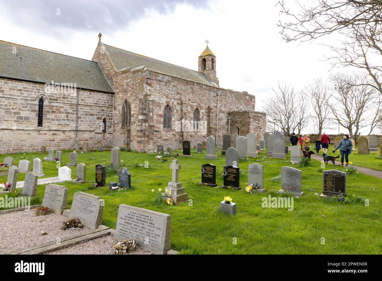 I visitatori della St Marys Church, o della St Mary the Virgin Church, chiesa in pietra del 12th° secolo a Lindisfarne o Holy Island, Northumberland, Regno Unito Foto Stock