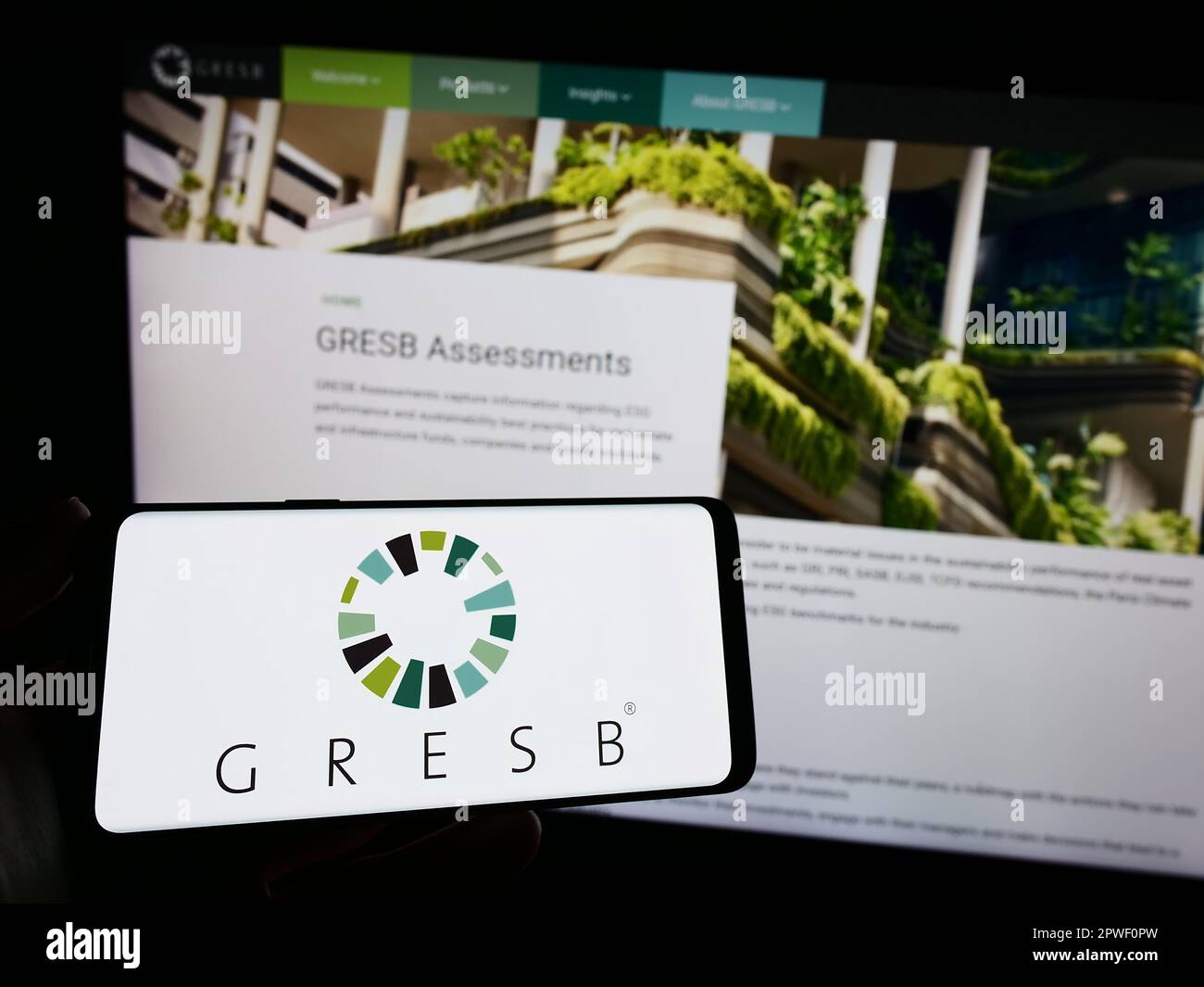 Persona che tiene in mano smartphone con il logo della fondazione ESG immobiliare olandese GRESB B.V. sullo schermo di fronte al sito web. Messa a fuoco sul display del telefono. Foto Stock
