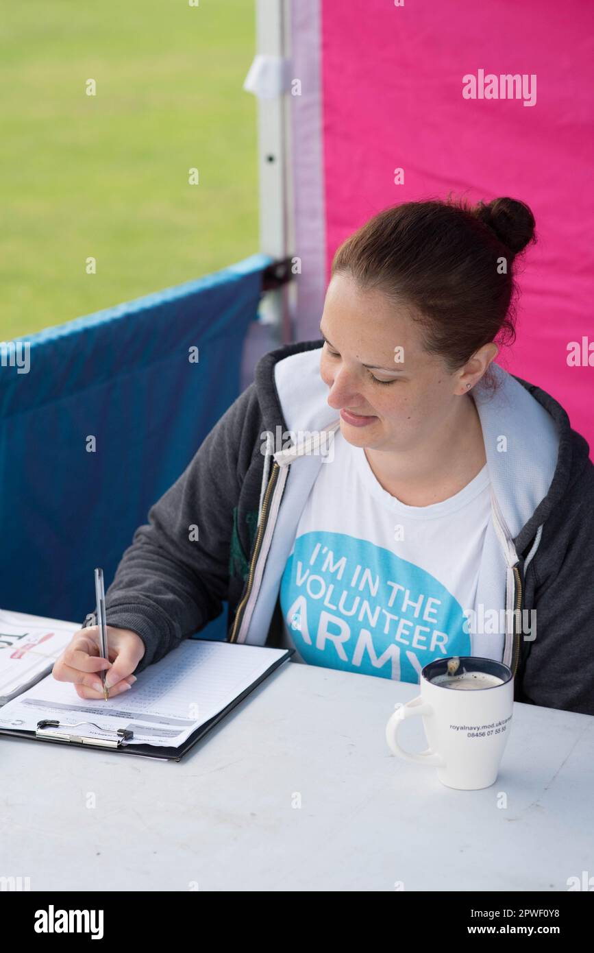 Donna che si dedica a Race for Life a Milton Keynes scrivendo su un clipboard Foto Stock