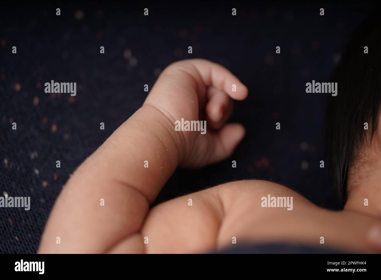 Piccolo corpo del bambino e mani sulla coperta blu marina dello sfondo. vista ravvicinata della mano carina del bambino il bambino sta comodamente adagiando in una coperta blu. Foto Stock