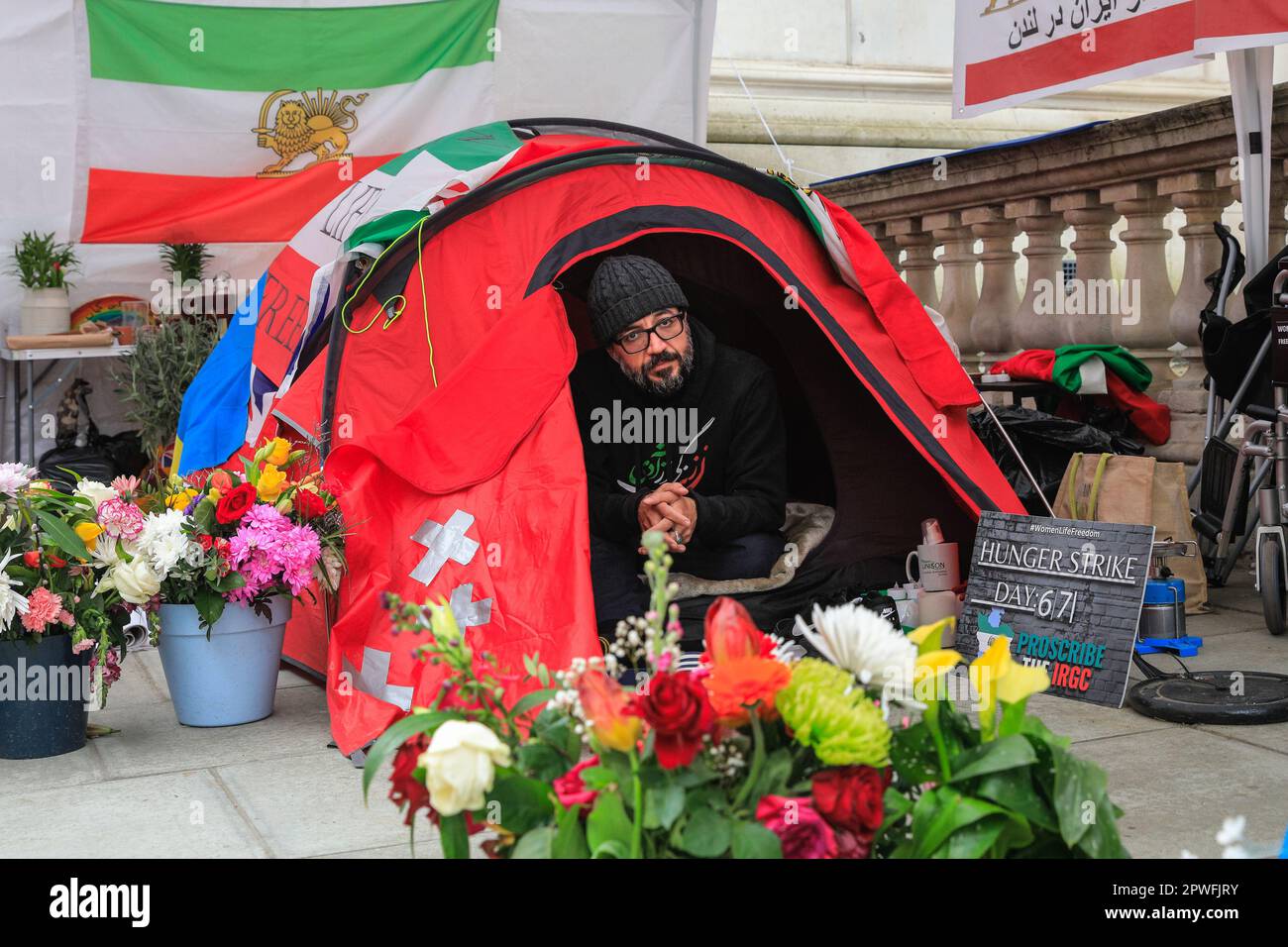 Londra, Regno Unito. 30th Apr, 2023. Vahid Beheshti nella sua tenda, che è ora surrogata da fiori e sostenitori. Beheshti è il giorno 67 del suo sciopero della fame al di fuori del Ministero degli Esteri britannico e chiede che l'IRGC (corpo della Guardia rivoluzionaria Islamica) sia inserito nella lista delle organizzazioni terroristiche internazionali da parte del Regno Unito. Ha avuto incontri con il FO, e ieri, diverse migliaia di sostenitori protestato in un raduno centrale di Londra per sostenere Beheshti. Il giorno 67, è in uno degli scioperi più noti della fame nel Regno Unito. Credit: Imageplotter/Alamy Live News Foto Stock