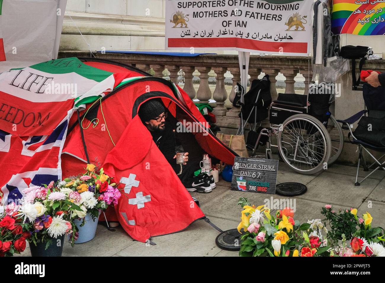 Londra, Regno Unito. 30th Apr, 2023. Vahid Beheshti nella sua tenda, che è ora surrogata da fiori e sostenitori. Beheshti è il giorno 67 del suo sciopero della fame al di fuori del Ministero degli Esteri britannico e chiede che l'IRGC (corpo della Guardia rivoluzionaria Islamica) sia inserito nella lista delle organizzazioni terroristiche internazionali da parte del Regno Unito. Ha avuto incontri con il FO, e ieri, diverse migliaia di sostenitori protestato in un raduno centrale di Londra per sostenere Beheshti. Il giorno 67, è in uno degli scioperi più noti della fame nel Regno Unito. Credit: Imageplotter/Alamy Live News Foto Stock