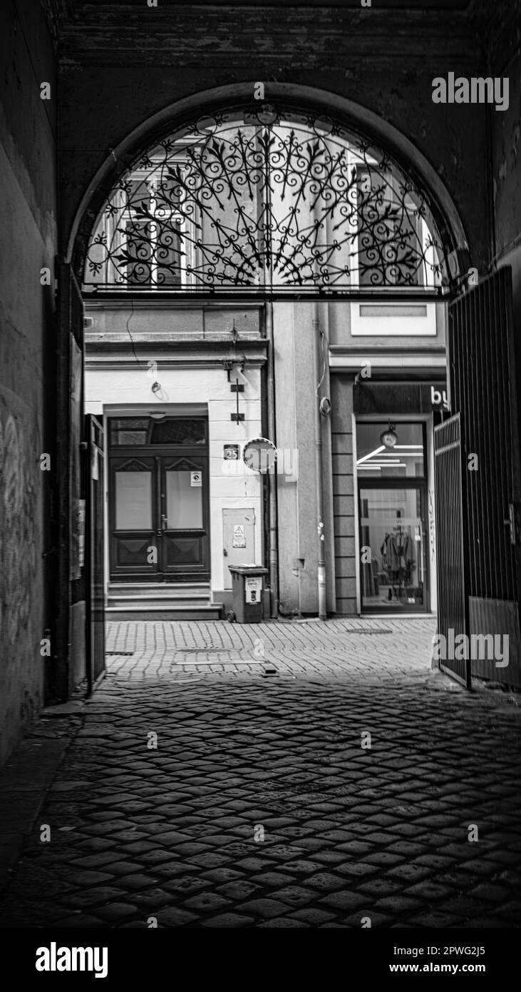 Bielsko-Biala una delle tante strade Una foto monocromatica di un grande ingresso architettonico illuminato dalla luce contro l'oscurità, incorniciato in nero Foto Stock