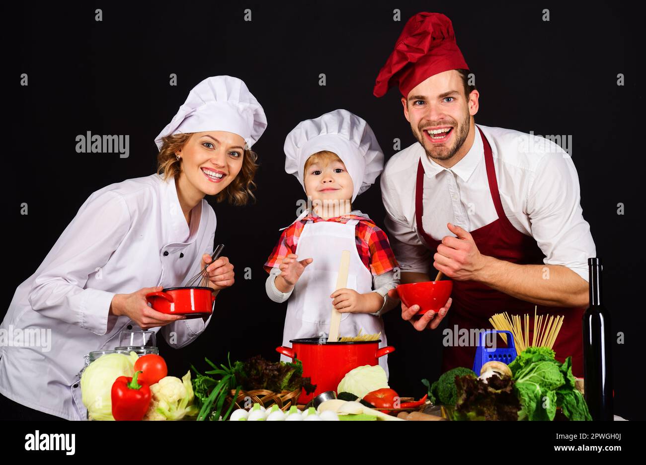 Famiglia felice che prepara insieme il cibo sano in cucina. I genitori insegnano al figlio come cucinare un pasto sano. La famiglia prepara la cena. Madre, padre e figlio Foto Stock