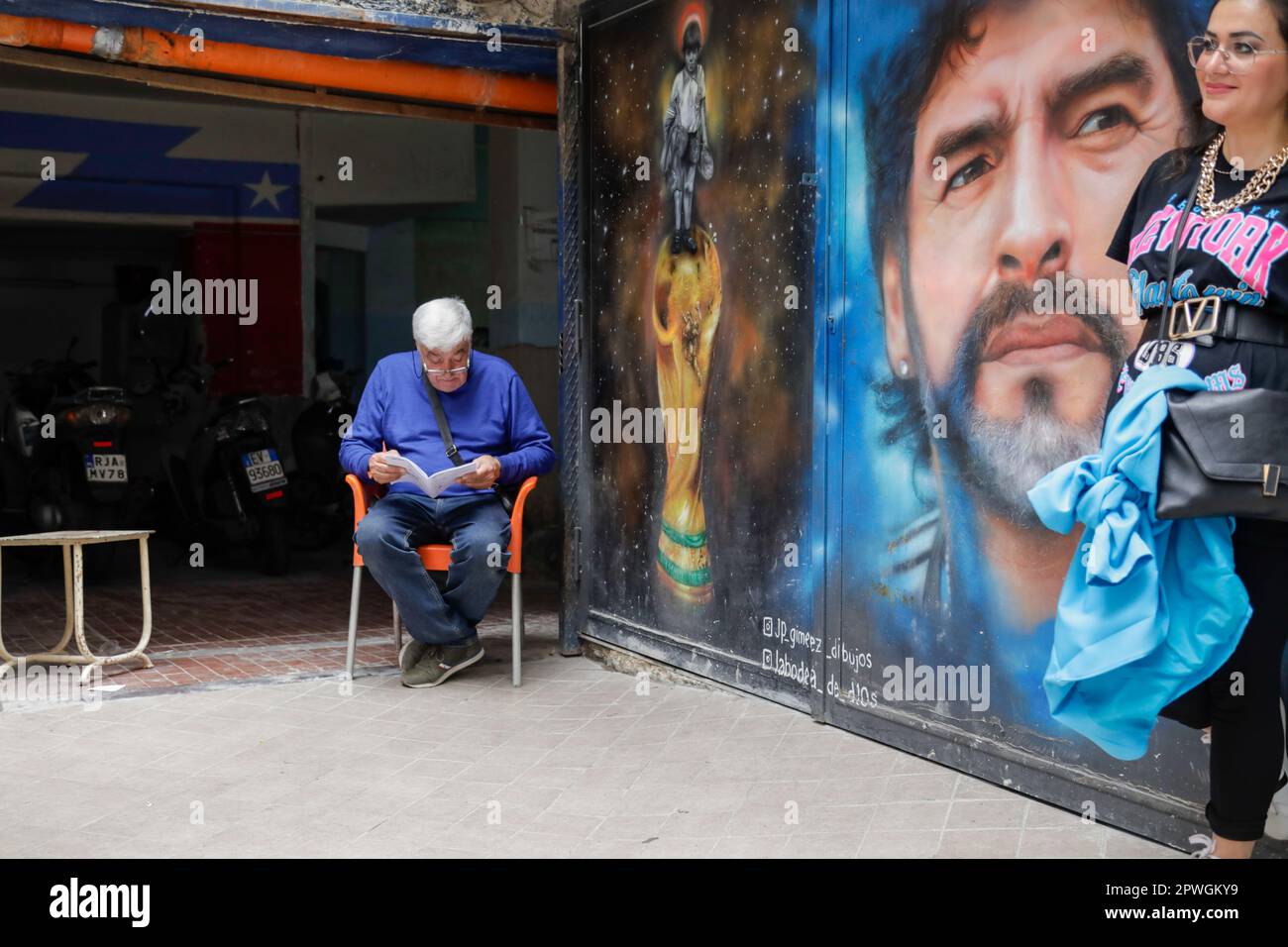 Napoli, Italia. 2023 aprile 30th, Napoli, Italia - un uomo sta leggendo un libro di fronte al suo garage nel bel mezzo del santuario di Maradona Credit: Marco Ciccolella/Alamy Live News Foto Stock