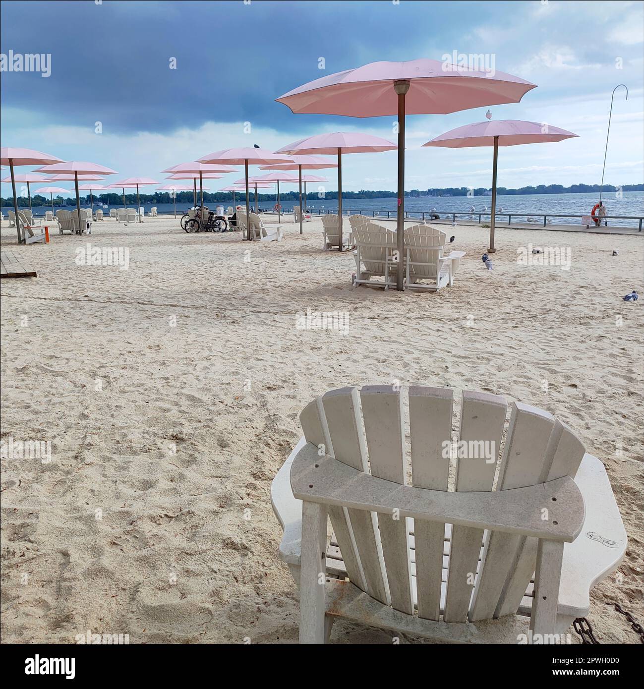 Un parco pubblico sulla spiaggia in città con ombrelloni rosa in una calda giornata estiva Foto Stock