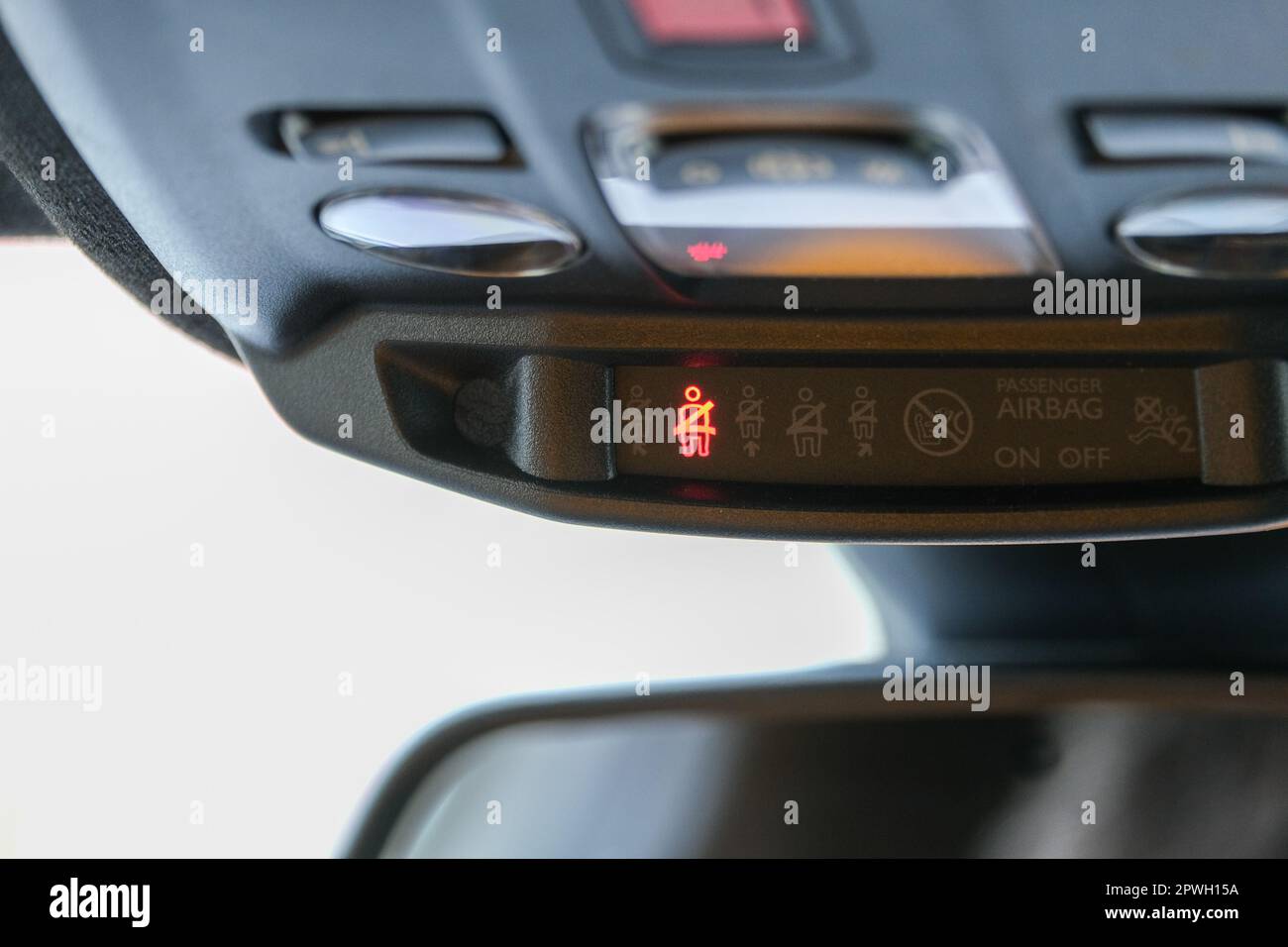 La spia della cintura di sicurezza e dell'airbag passeggero si accende sullo specchietto retrovisore interno della vettura sotto il faro. Cartelli all'interno dell'auto. Messa a fuoco selettiva. Foto Stock
