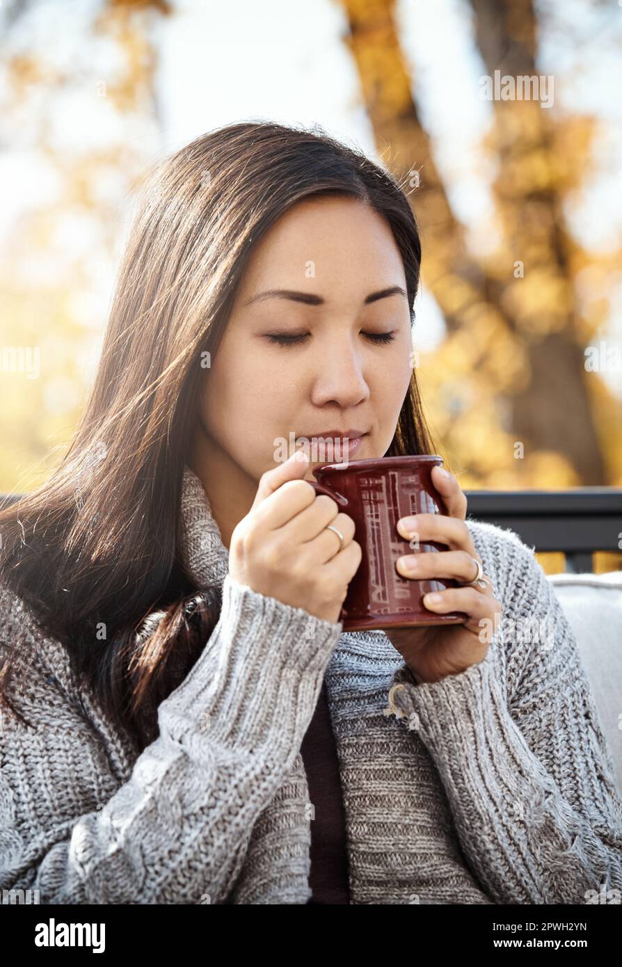 Il suo autunno, tempo di rallentare le cose. una giovane donna attraente che ha una pausa caffè rilassante in una giornata autunnale in un giardino. Foto Stock
