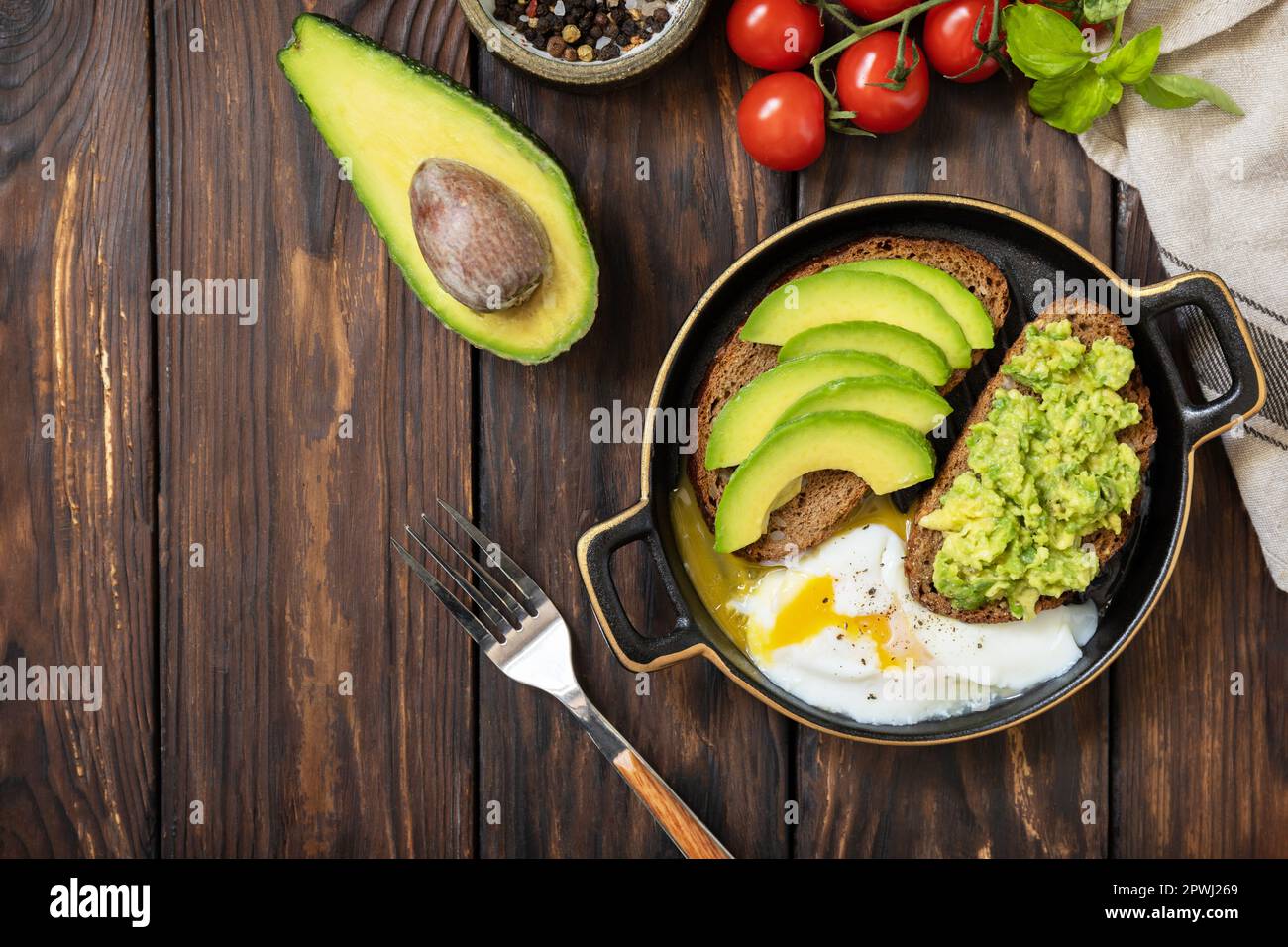 Pane integrale toast avocado a fette e uovo in camicia su un tavolo rustico. Colazione sana, sandwich con avocado e uova. Vista dall'alto. Spazio di copia. Foto Stock