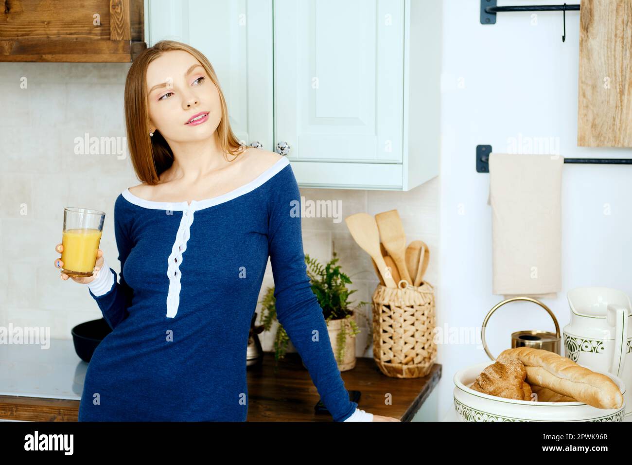 Donna sognante in cucina con bicchiere di succo Foto Stock