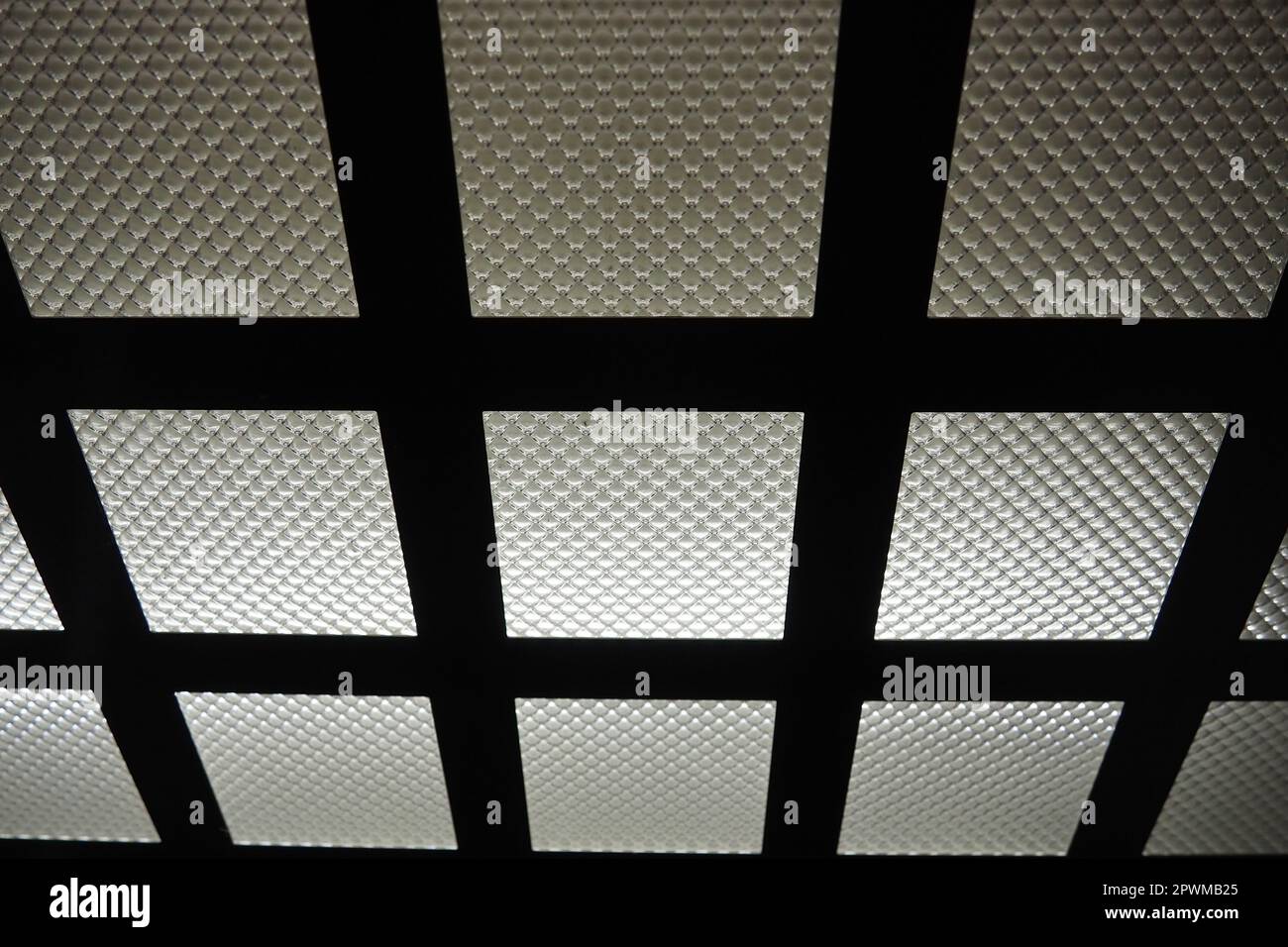 Luce LED elettrica nell'ascensore. Il soffitto dell'ascensore. Sorgente luminosa a scacchi, linee metalliche orizzontali e verticali e vetro ondulato. Foto Stock