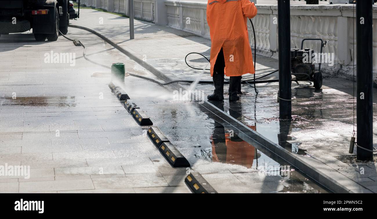 Pulizia di pietre da pavimentazione sporche. Lavare la fontana sotto un potente getto Foto Stock