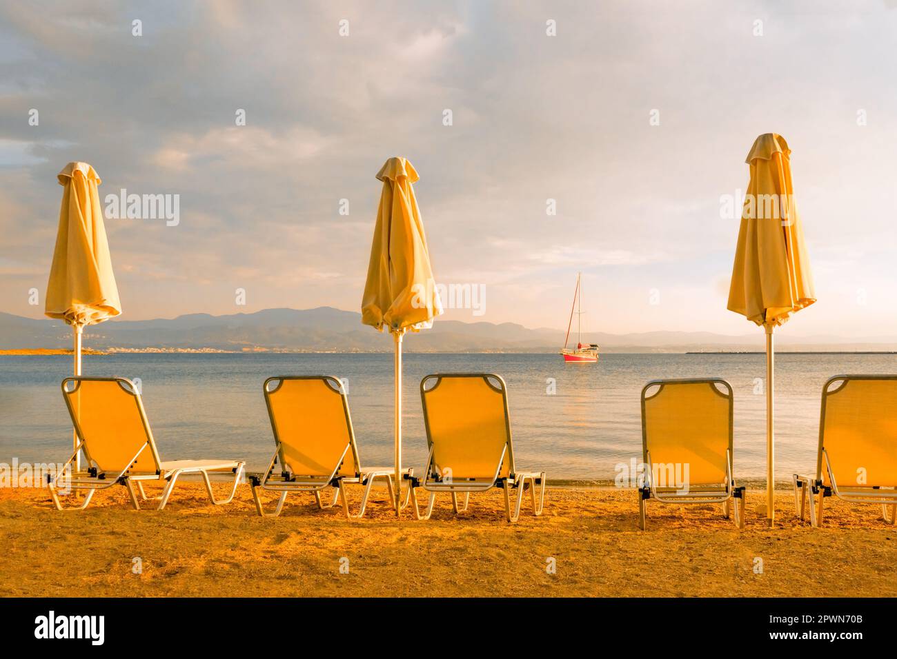 Sedie da spiaggia vuote ombrellone sdraio spiaggia sdraio sdraio mare yacht spiaggia barca a vela mare spiaggia tramonto barca a vela. Mare sfondo vacanza mare Foto Stock